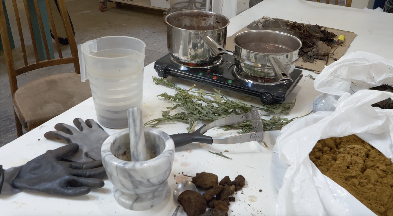 Various tools and natural materials sit on a white table in a studio workshop.