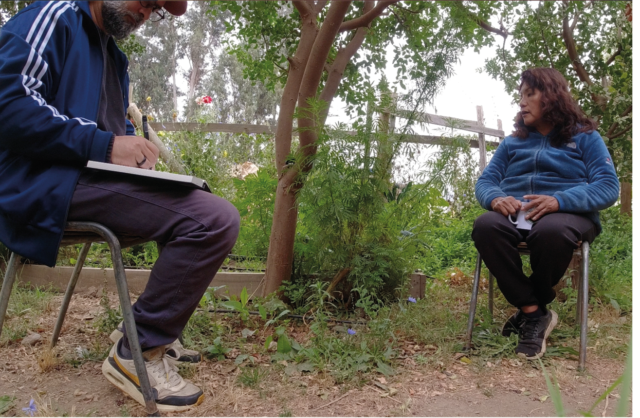 In the photo, the researcher is chatting with Silvia and huacatay, who are sitting in the vegetable garden.