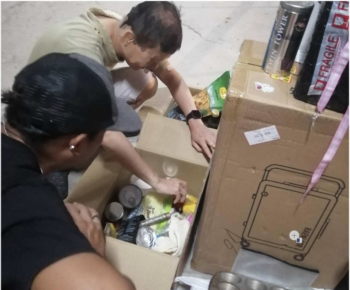 Two volunteers sorting through boxes of food items
