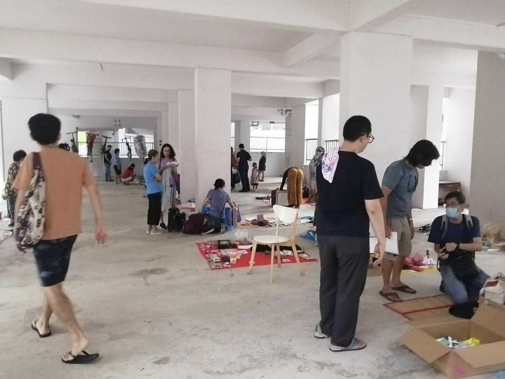 People sorting and viewing items in a large covered hall