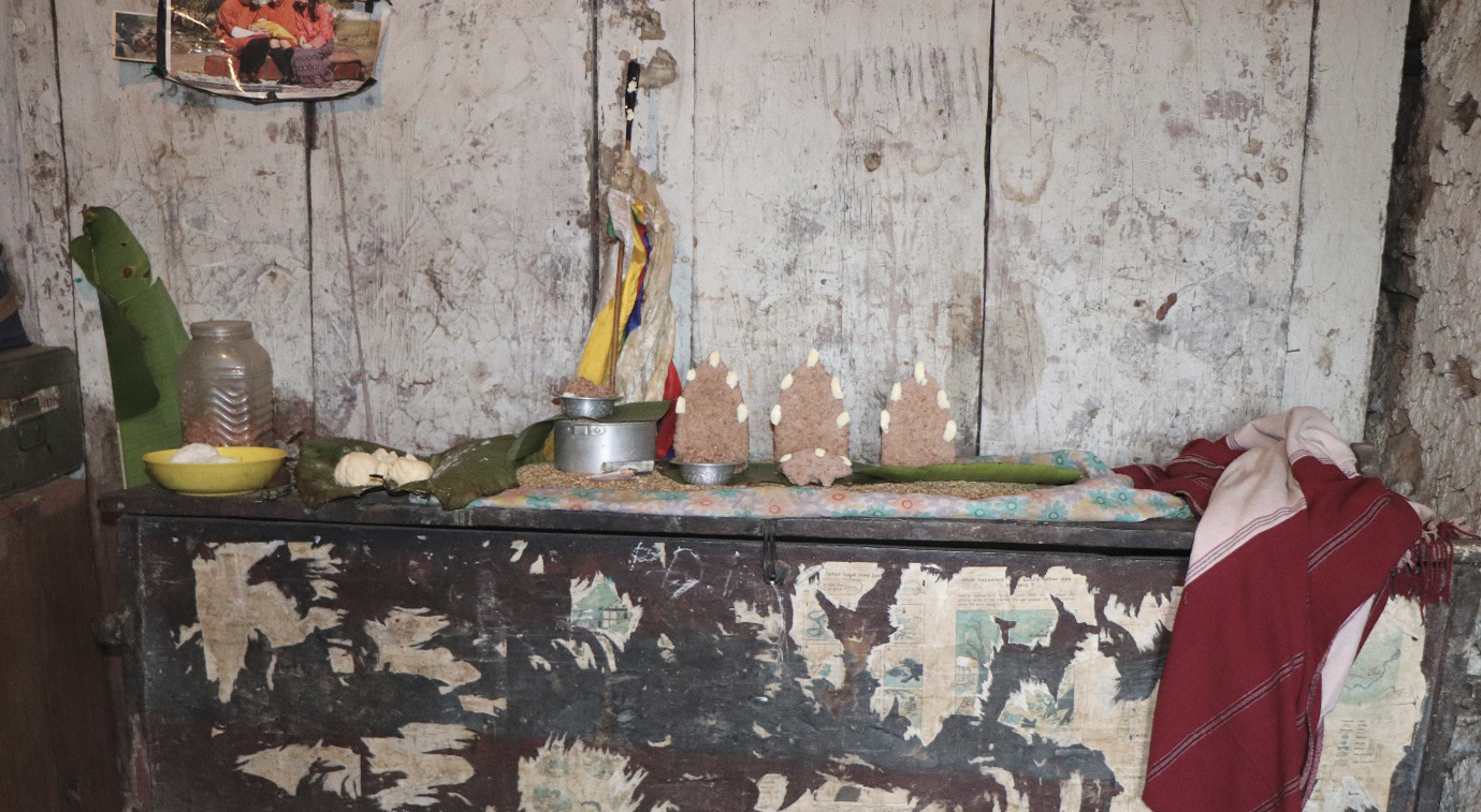 Offerings of dough and dairy to local deities placed on an undecorated shelf in the corner of a room.