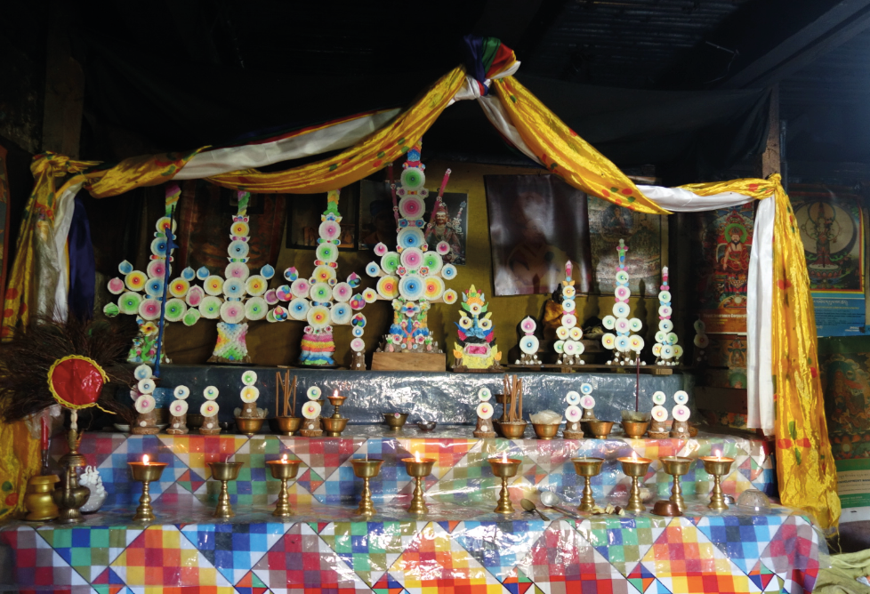 Multicoloured rice and butter cakes, made as ritual offerings, on a decorated Buddhist altar.