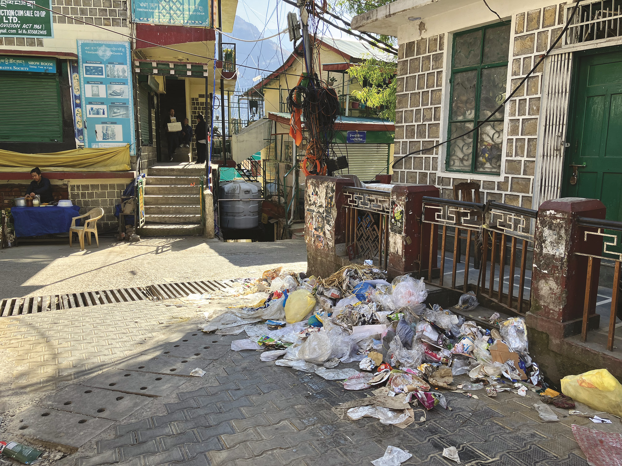 Photograph of a street with a pile of rubbish that has been swept to one side.